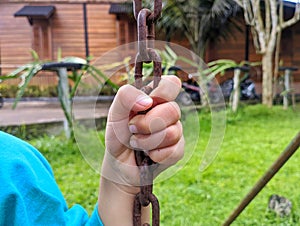 child's hand holding the iron swing rope. atmosphere on the playground