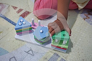 Child& x27;s hand, playing with montessory toys. Geometry puzzle. photo