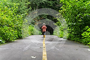 a child in yellow boots runs along the path in the park