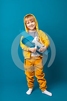 A child in a yellow sweatshirt with skis in his hands. Children`s leisure and sports concept