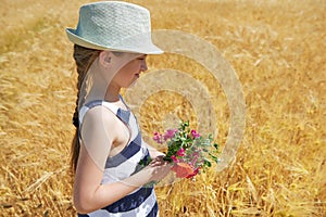Child is in the yellow wheat field, bright sun, summer landscape
