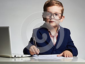 Child.Young business boy in office. kid in glasses writing pen