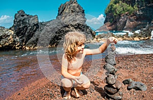 Child with zen stones on sea beach, meditation, spa and harmony. Calm balance concept. Kids play on the beach.