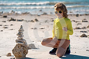 Child with zen stones on sea beach, meditation, spa and harmony. Calm balance concept. Kids play on the beach. Keep calm