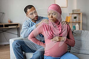 Childbirth Concept. Pregnant Black Muslim Woman Feeling Abdomenal Pain At Home photo