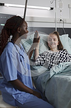 Childcare healthcare facility staff high fiving ill kid under medical treatment