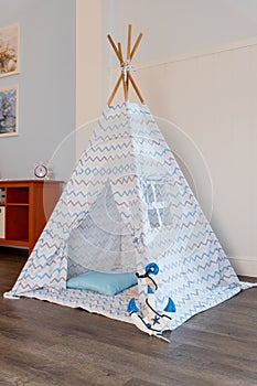 Childen`s room corner with a beautifully decorated play tipi tent and a pillows.Cozy play tent for kids as element of