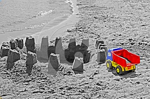 Childen`s truck plastic toy with sand castle on the beach