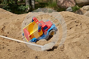 Childhood and adult life: a junk truck and a real shovel on a pile of sand