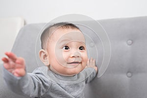 Childhood, babyhood and people concept - happy little baby girl sitting on sofa at home