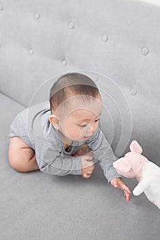 Childhood, babyhood and people concept - happy little baby girl sitting on sofa at home