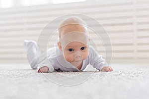 Childhood, babyhood and people concept - little baby boy or girl crawling on floor at home