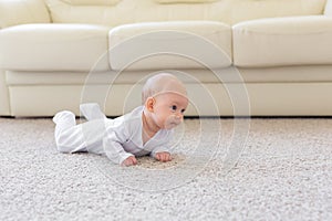 Childhood, babyhood and people concept - little baby boy or girl crawling on floor at home