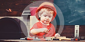 Childhood concept. Boy play as builder or repairer, work with tools. Kid boy in orange hard hat or helmet, study room