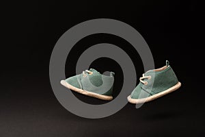 Childhood concept with levitation effect. Flying shoes of newborn baby on black background