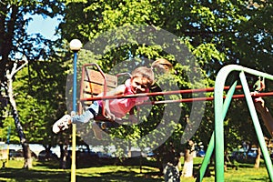 Childhood daydream .teen freedom. Small kid playing in summer. Playground in park. Happy laughing child girl on swing