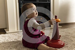 childhood, development, skills, motility games - little authentic child baby toddler girl puts rings on pyramid playing