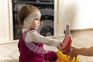 childhood, development, skills, motility games - little authentic child baby toddler girl puts rings on pyramid playing