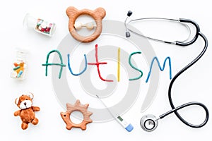 Childhood diseases. Word autism near stetoscope, pills, toys on white background top view