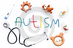 Childhood diseases. Word autism near stetoscope, pills, toys on white background top view