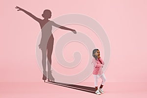 Childhood and dream about big and famous future. Conceptual image with girl and shadow of fit female figure skater on