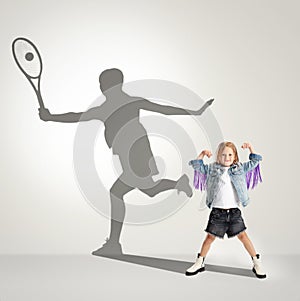 Childhood and dream about big and famous future. Conceptual image with girl and shadow of female tennis player on light