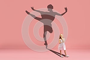 Childhood and dream about big and famous future. Conceptual image with girl and shadow of fit ballerina dancing on coral