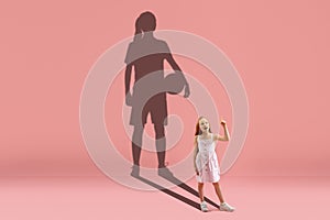 Childhood and dream about big and famous future. Conceptual image with girl and shadow of fit basketball or soccer