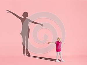 Childhood and dream about big and famous future. Conceptual image with girl and shadow of fit female figure skater on