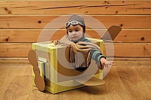 Childhood dream imagination concept . Little cute boy playing with a cardboard airplane.