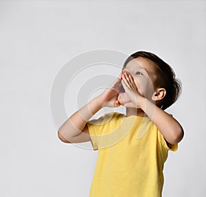 childhood, expressions and people concept - little boy in yellow t-shirt with blank space, calling someone or shouting