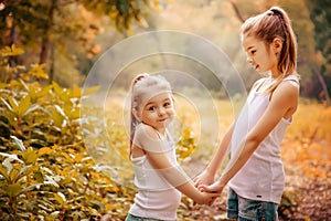 Childhood, family, friendship and people concept - two happy kids sisters hugging outdoors.