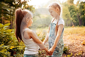 Childhood, family, friendship and people concept - two happy kids sisters hugging outdoors.