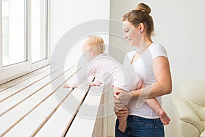 Childhood, family and motherhood concept - Mother with her baby playing at living room