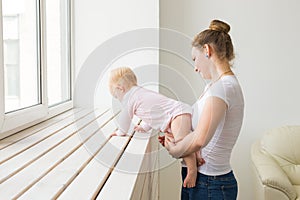 Childhood, family and motherhood concept - Mother with her baby playing at living room