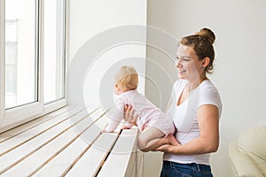 Childhood, family and motherhood concept - Mother with her baby playing at living room