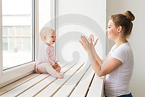Childhood, family and motherhood concept - Mother with her baby playing at living room