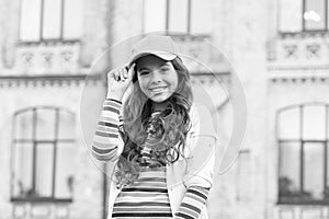 Childhood happiness. Happy girl with curly hair wearing cap. Child smiling outdoors. Beauty and fashion. You would not