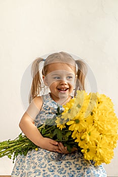 Childhood, holidays, flowers, gifts concept - little cute three year old girl with two ponytails on her head in blue