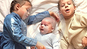 Childhood, infancy, family, sleep, rest concept - close up of three joyful happy children, newborn baby and 3-4 year old