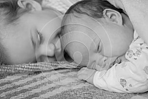 Childhood, infancy, family, sleep, rest, love concepts .black and white close up view of two children, newborn baby and