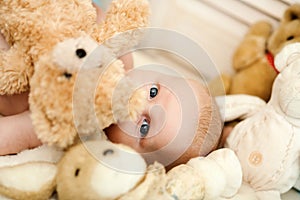 Childhood and innocence concept. Baby covered with his teddy bear