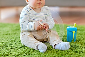 Baby boy on floor and eating rice cracker at home