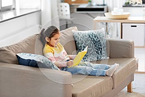 Happy smiling little girl reading book at home