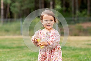 happy baby girl with soap bubble blower in summer