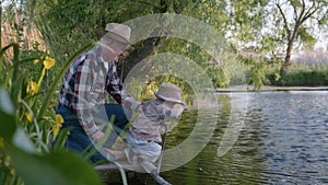 Childhood, little cute male child together with his beloved grandfather, fisherman learns to fish in pond with fishing