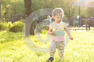 Childhood, nature, summer, parks and outdoors concept - portrait of cute blond-haired little boy in striped multi