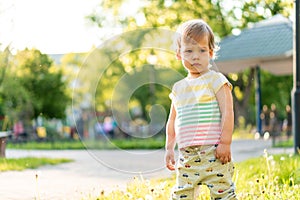 Childhood, nature, summer, parks and outdoors concept - portrait of cute blond-haired little boy in striped multi