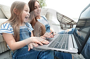 Happy mother with adorable little girl with laptop