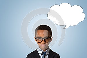 Childhood and people concept-little african american boy with glasses in business suit over blue background with empty thought